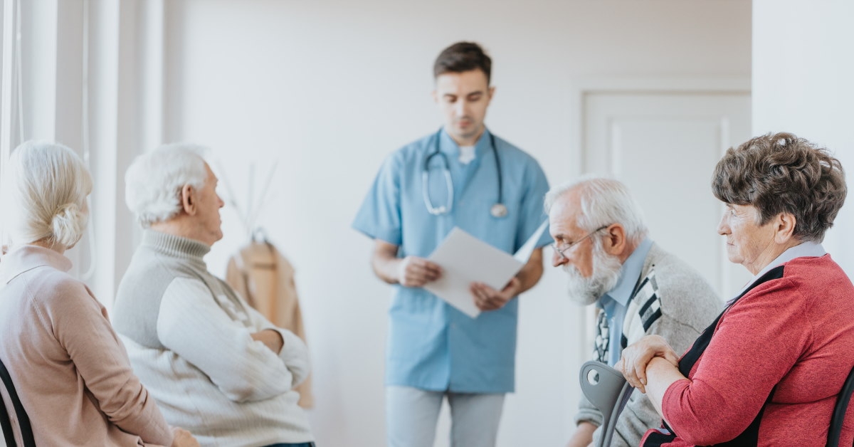 male nurse wearing scrubbers and stethoscope reviewing reports while standing in waiting area