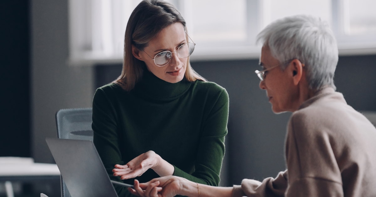 young woman explaining work to senior boss in office