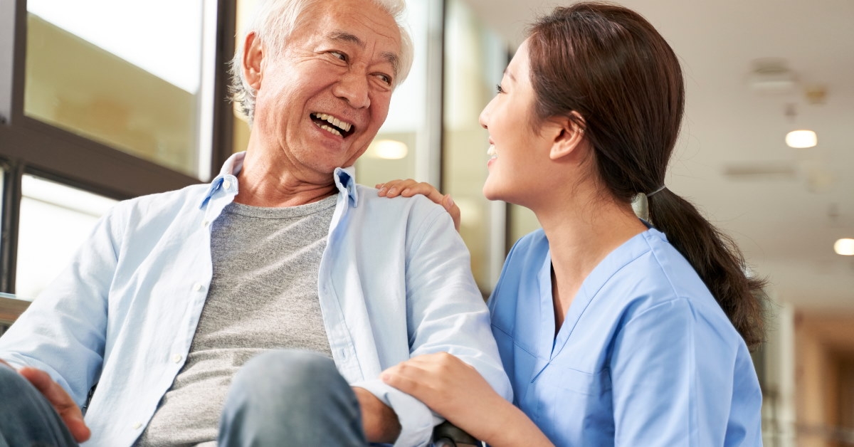 female nurse providing emotional support to an elderly man in a wheelchair