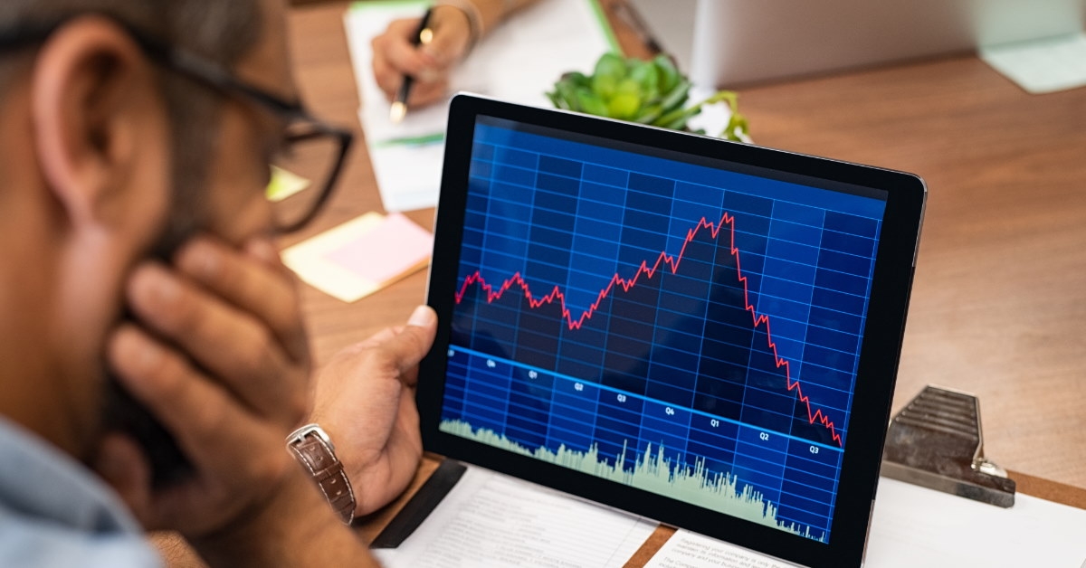 man checking stock market graphs on tablet at work.