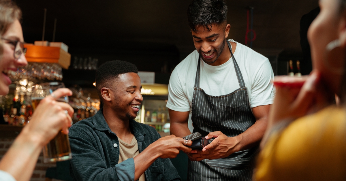 friends out for dinner paying with cellular device 