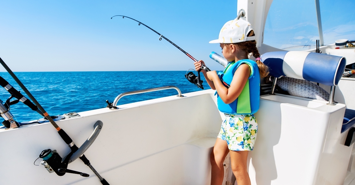little girl with a fishing rod fishing from the boat