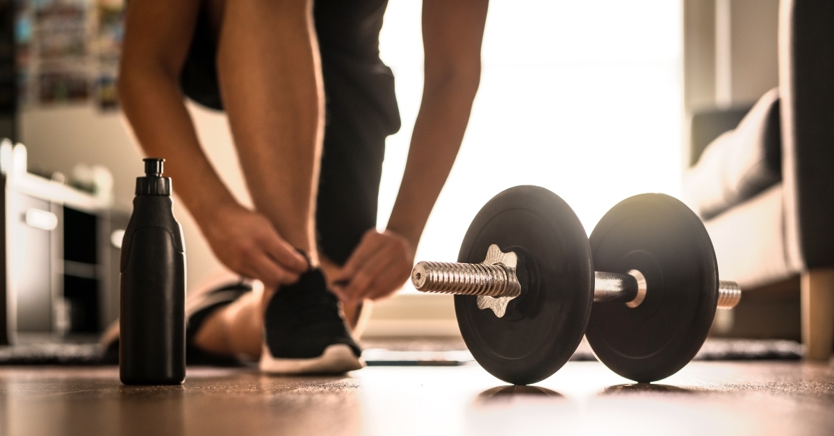 man in sneakers tying shoelaces in sunlight 