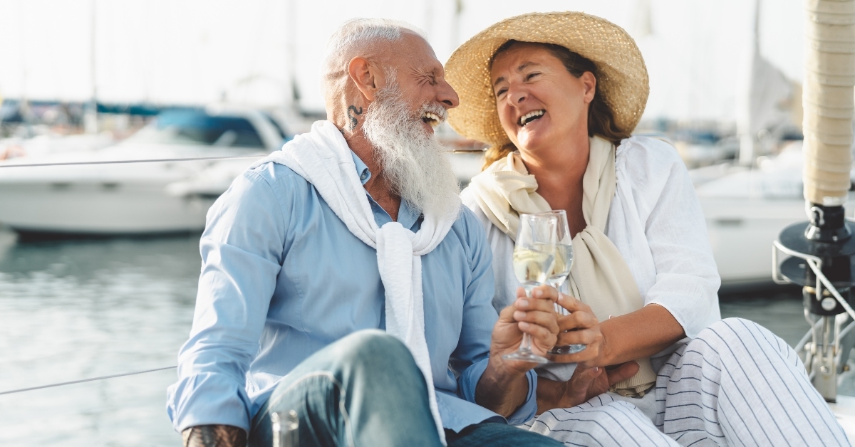 senior couple toasting champagne on sailboat