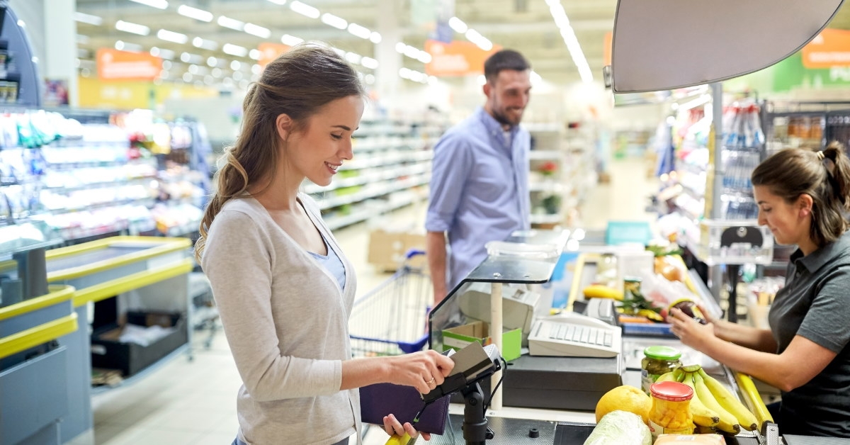 woman using card to pay money at grocery store 