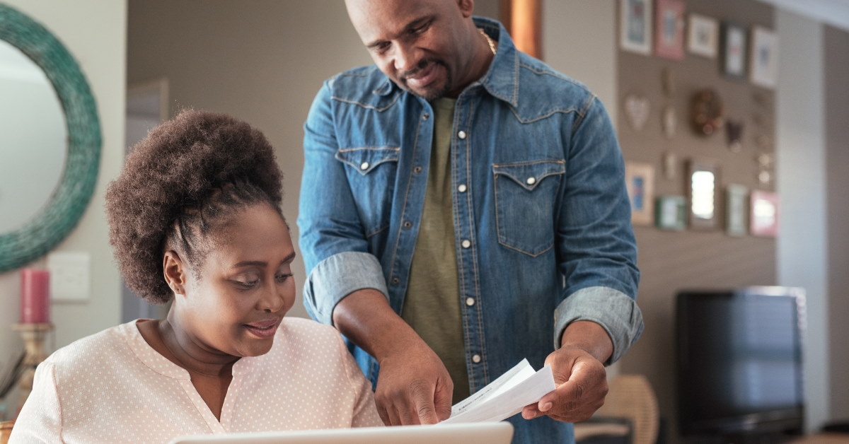 happy african american couple at homes paying online utility bills using laptop