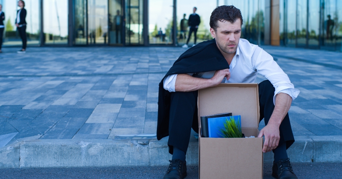fired businessman sitting on street