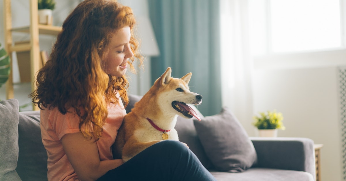 happy woman sitting on couch in lounge hugging her beloved dog