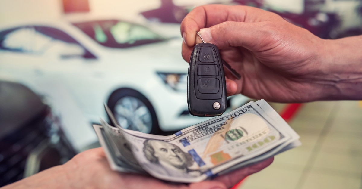 male car dealer giving keys to new owner in exchange for money 