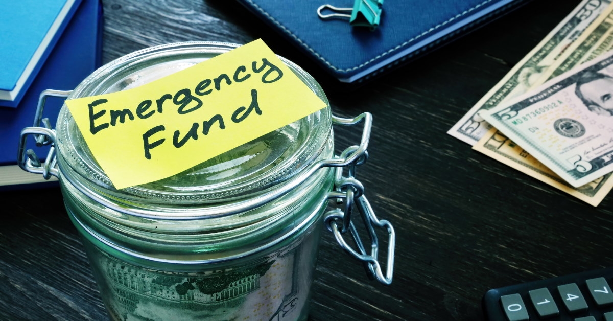 Glass jar full of money with emergency fund sticky note label 