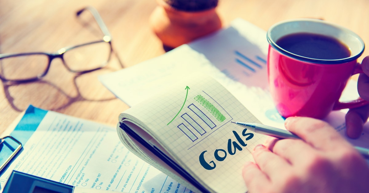 notepad with goals written over it on table next to calculator 