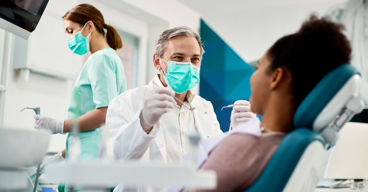 african american woman receiving dental procedures from dentist wearing mask at clinic