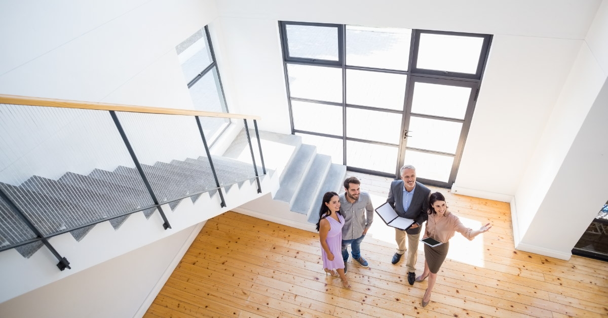 female real estate agent along with male real estate advisor showing new house to young couple