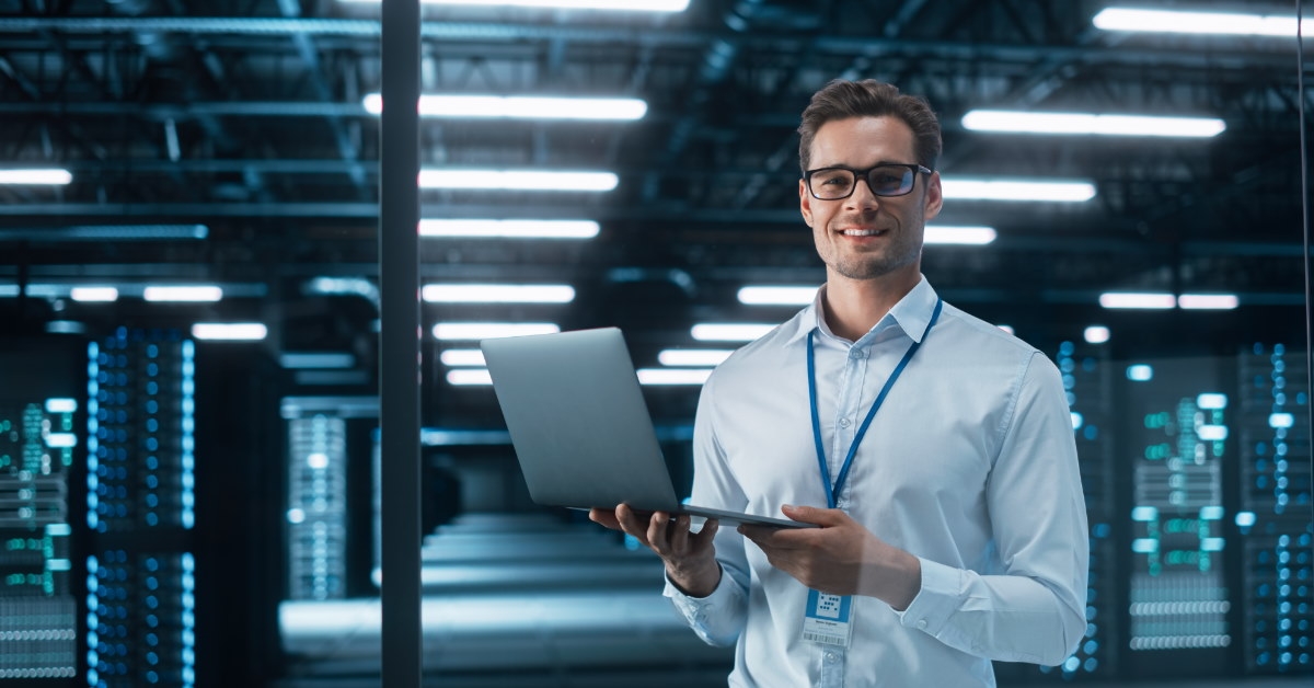 male data engineer holding laptop in hand while working late at night