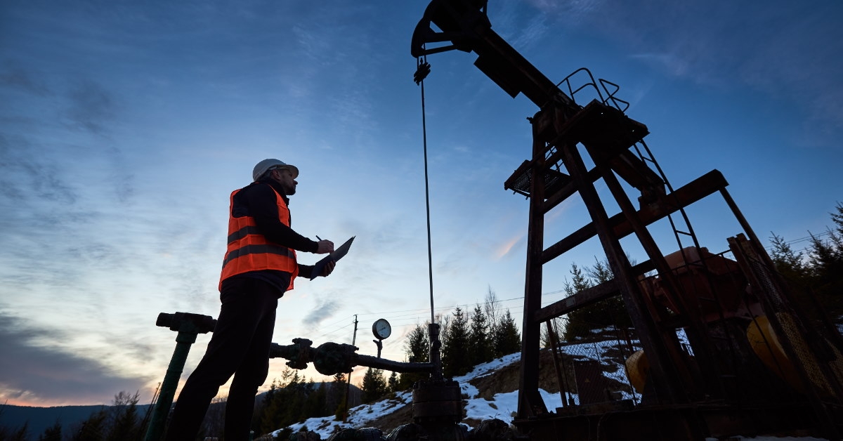 male petroleum engineer wearing neon vest and holding checklist to inspect 