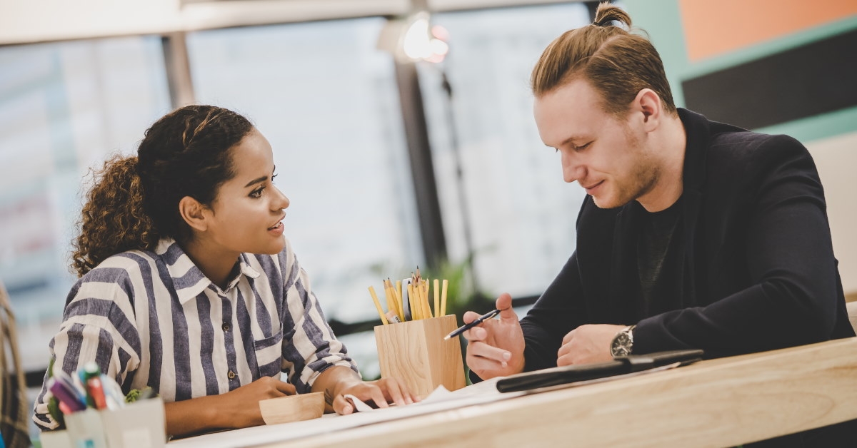 male and female colleagues sitting at table brainstorming about innovative ideas