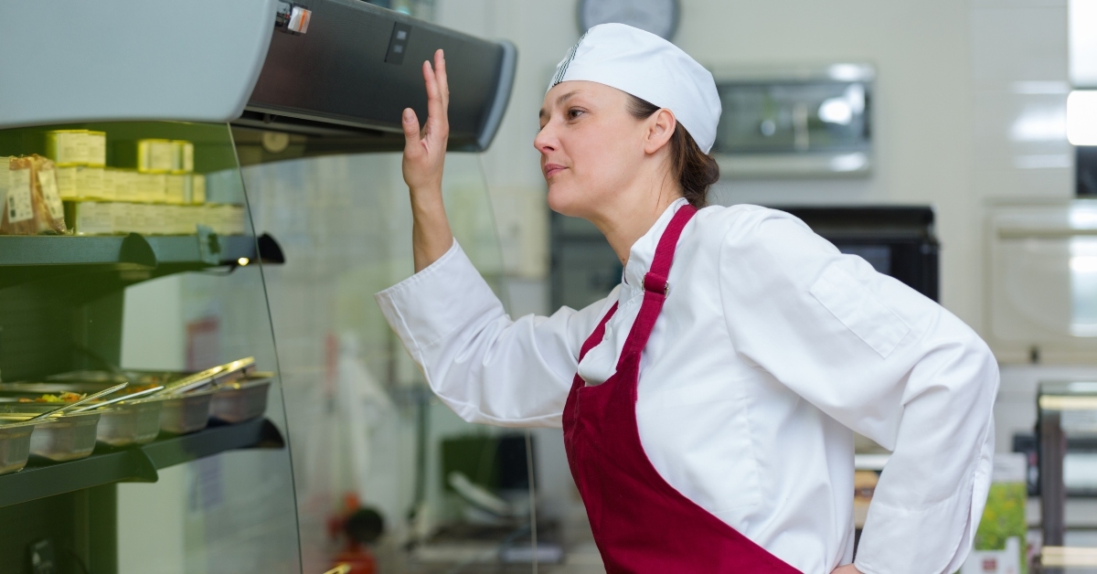 female worker checking temperature of chiller unit