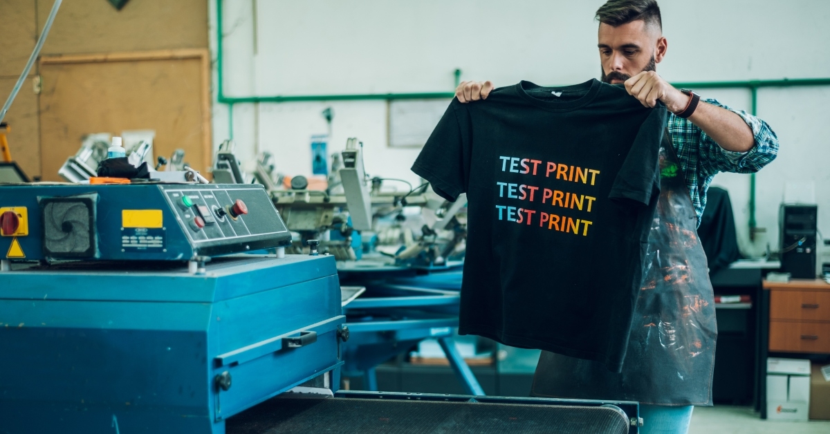 male worker using a drying oven for t-shirt
