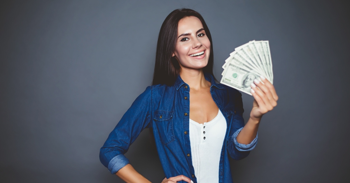 young woman joyfully holding in her hand a lot of dollars