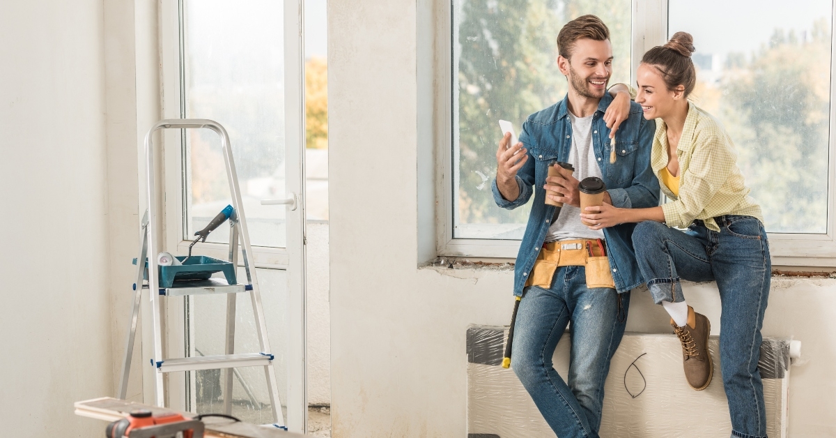 young couple holding paper cups and using smartphone