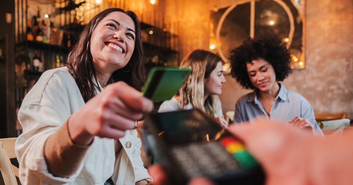 Woman paying bill with a contactless credit card in a restaurant