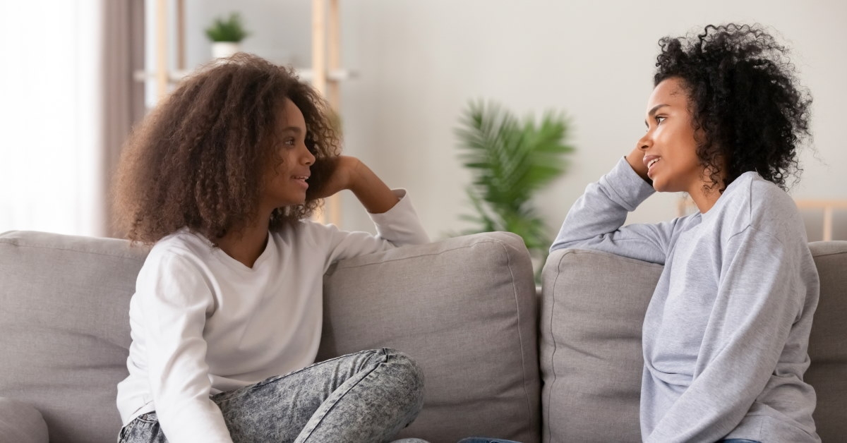 african american women sitting on couch talking to each other at home