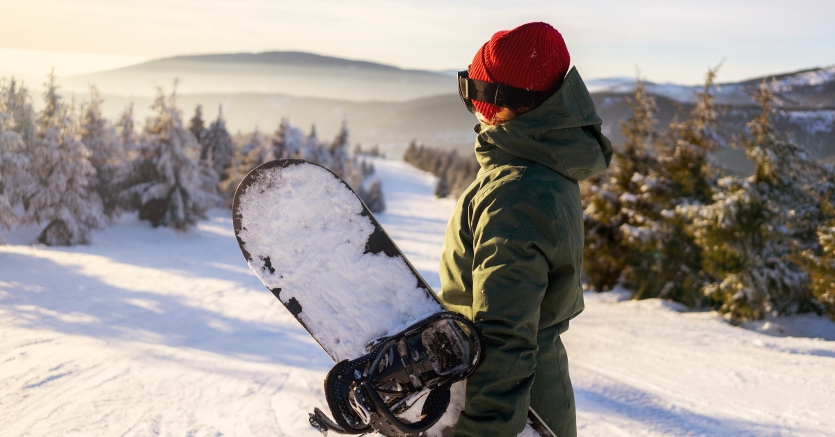girl snowboarder stands with snowboard