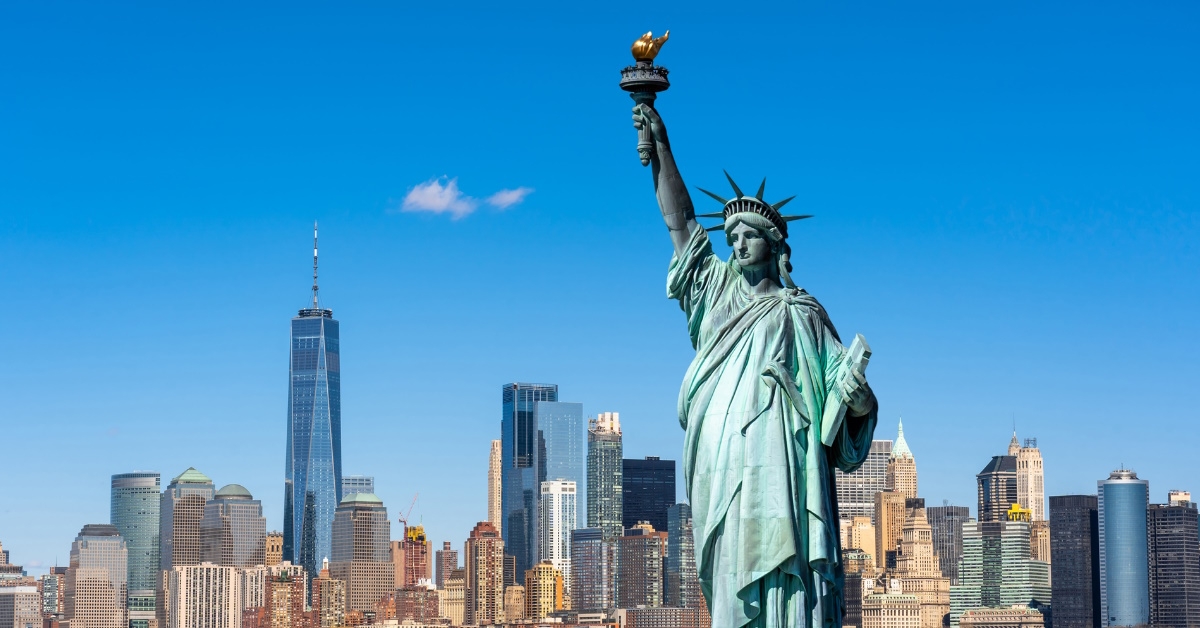 statue of liberty during day time over new york city scape