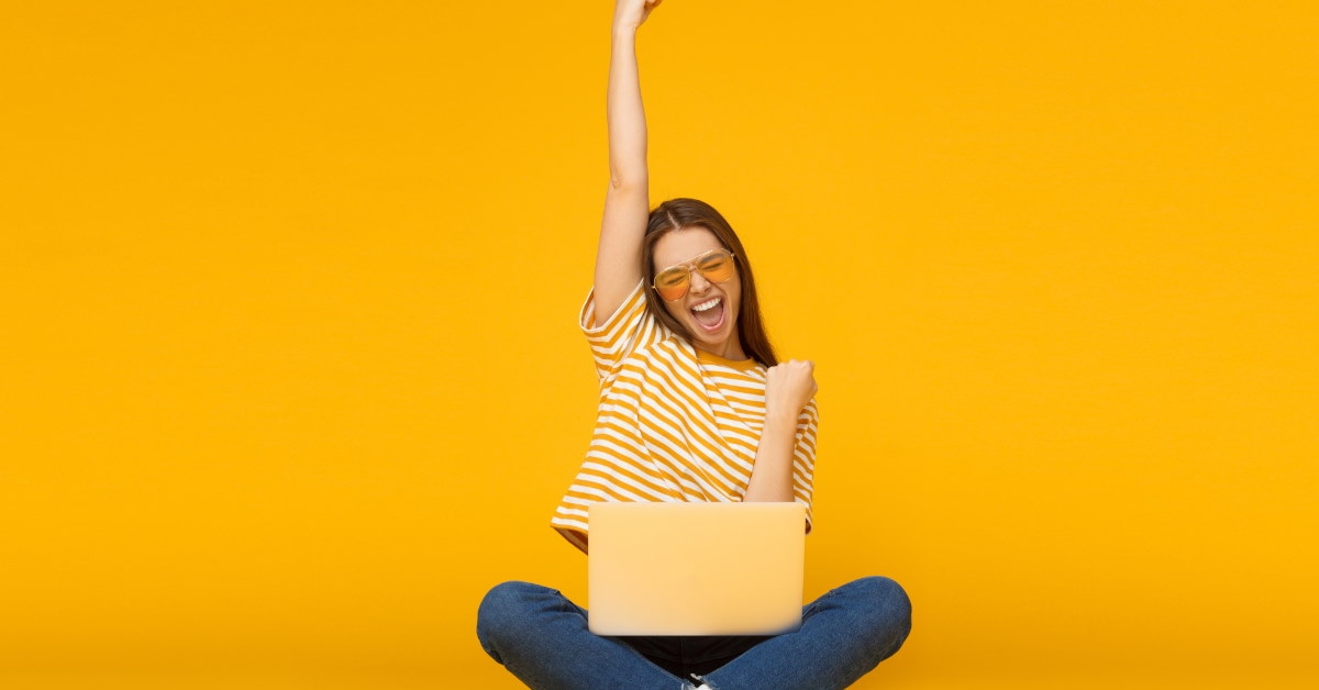 woman using laptop and feeling happy in front of yellow background