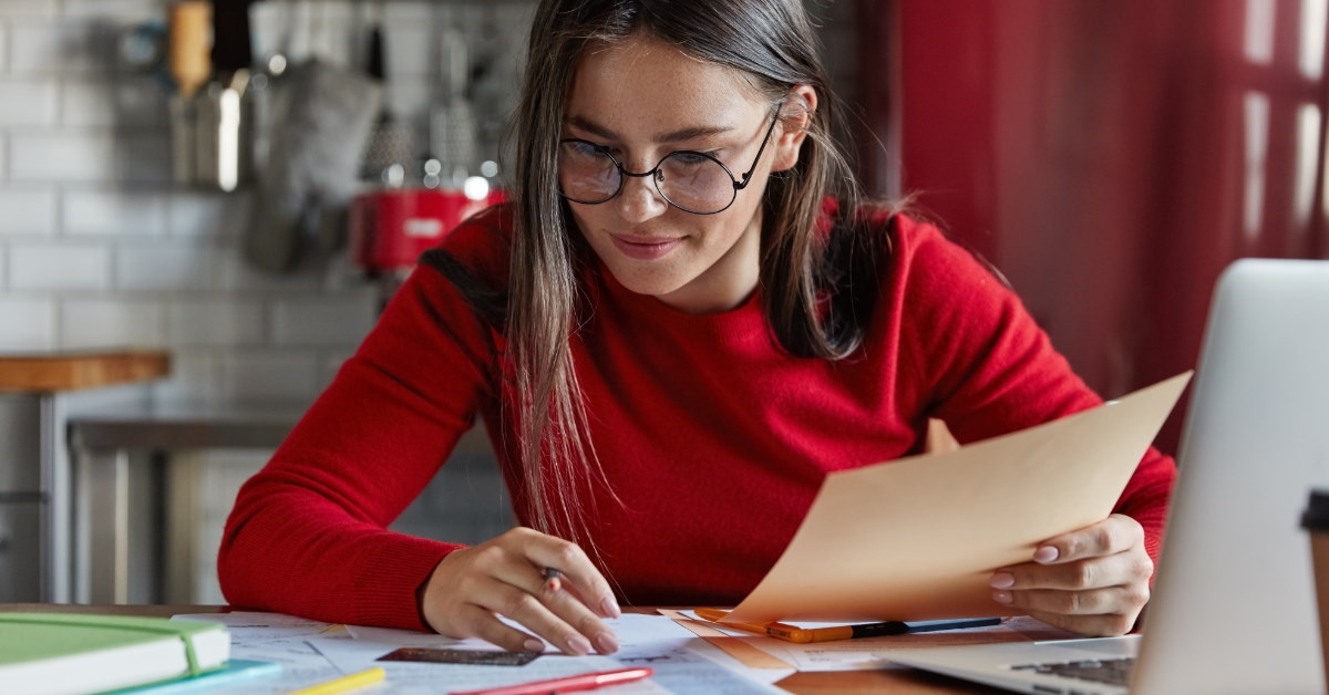 woman reviewing bills on laptop while sitting at a table.