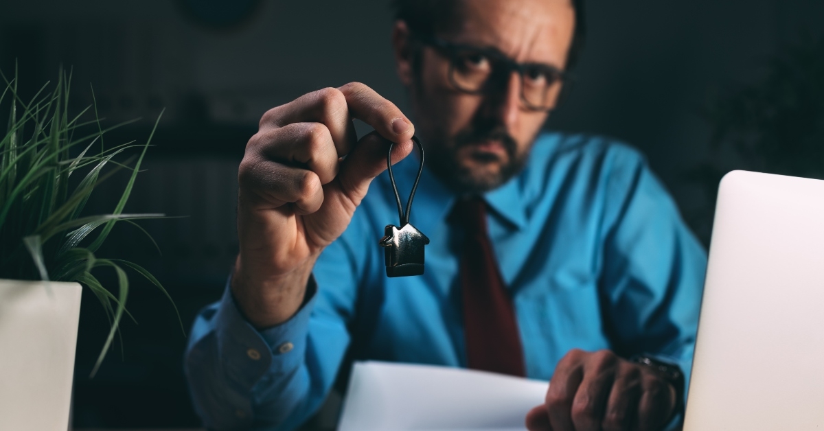 broker in dark office with house shaped keychain