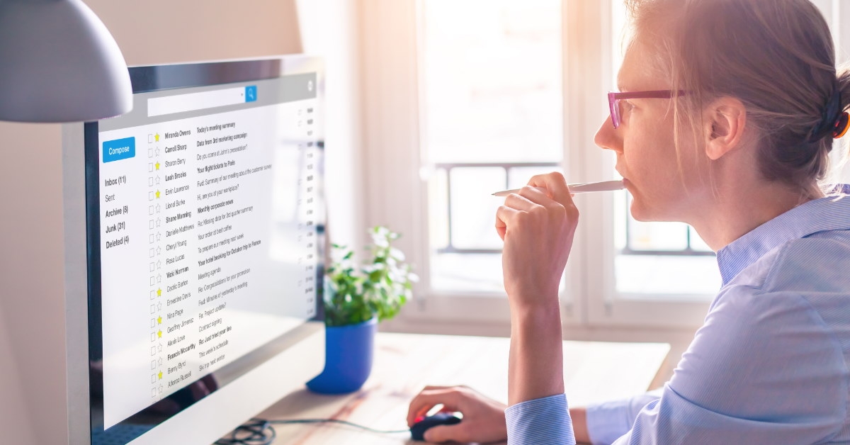 businesswoman sitting at table using computer to read emails on screen