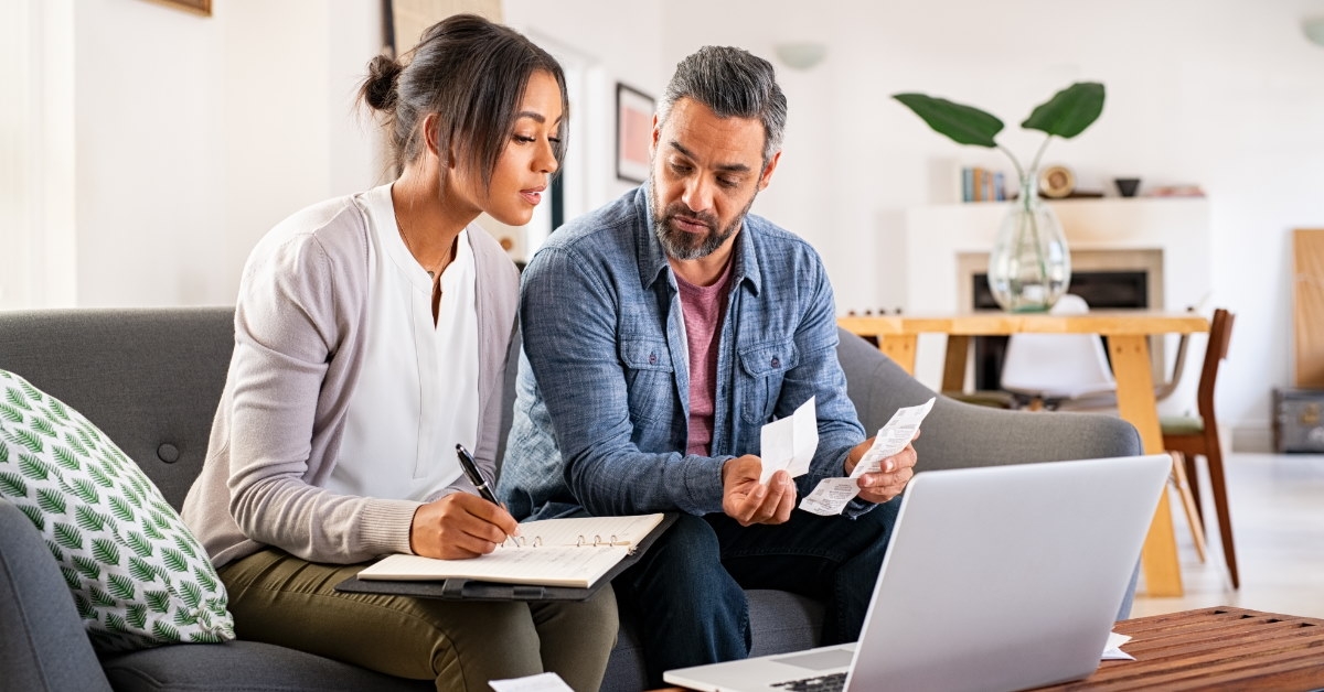 couple sitting on couch reviewing receipts to calculate bills at home