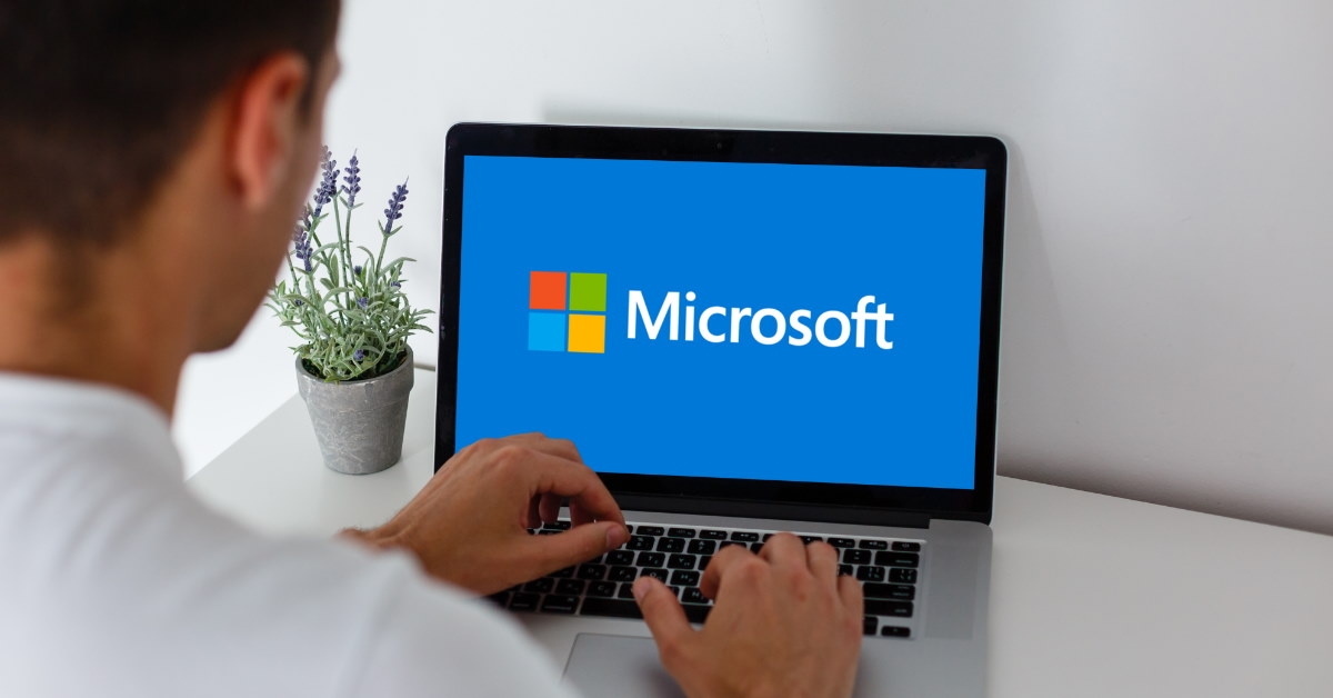 man working on a laptop displaying the microsoft logo.