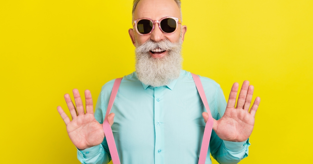 elder man in teal shirt sunglass laughing while touching suspenders