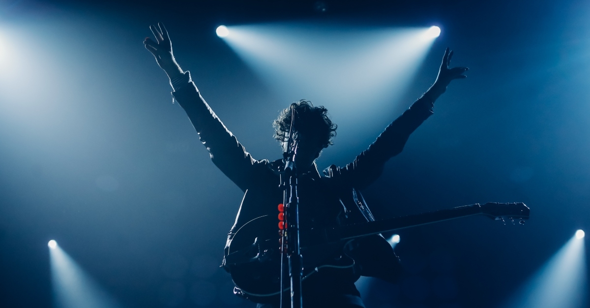 frontman on a stage with the hands raised up 