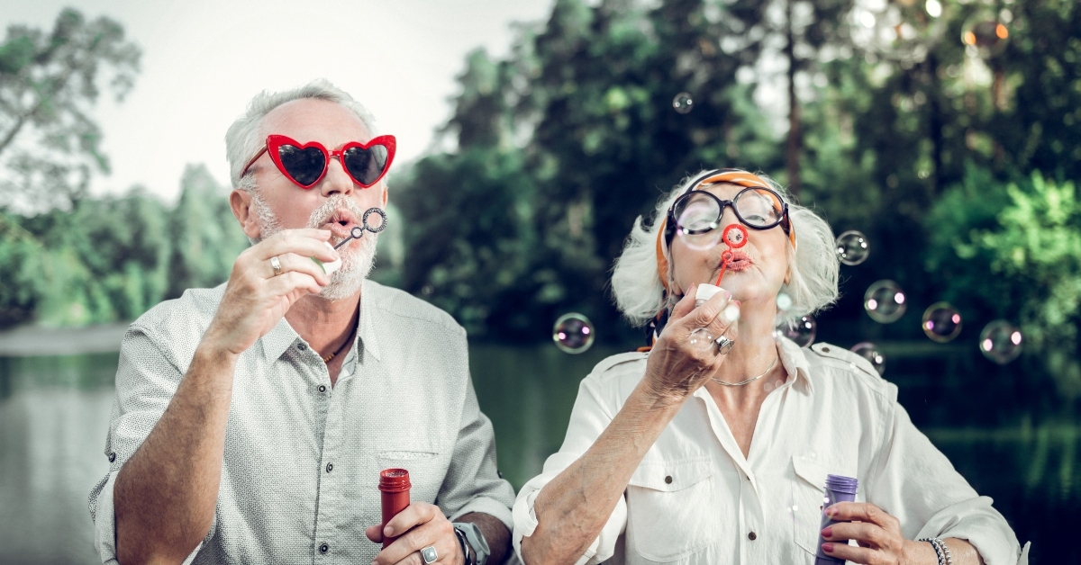 happy couple in funny sunglasses blowing bubbles