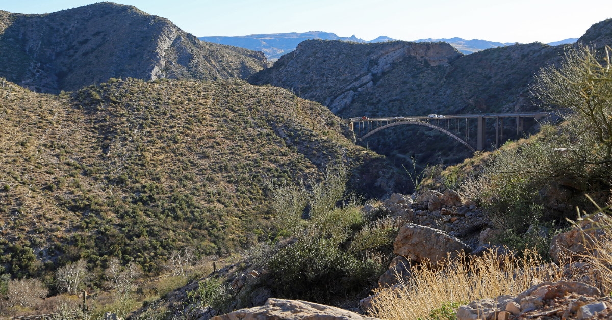green landscape near mountains and queen creek bridge in daylight.