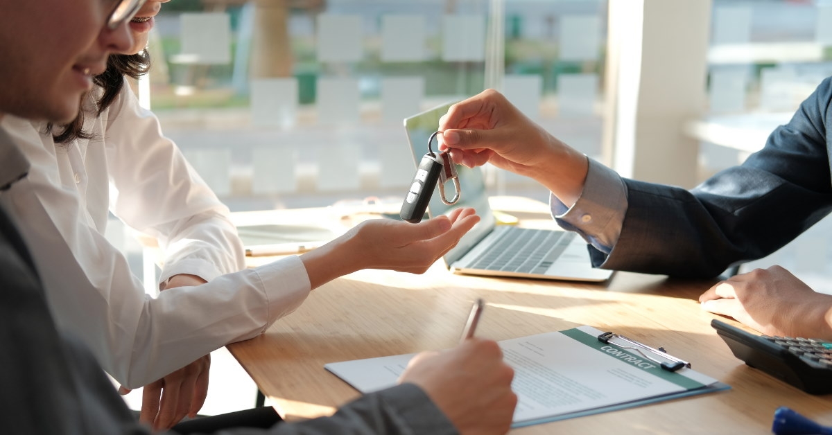 sales manager giving car keys to woman