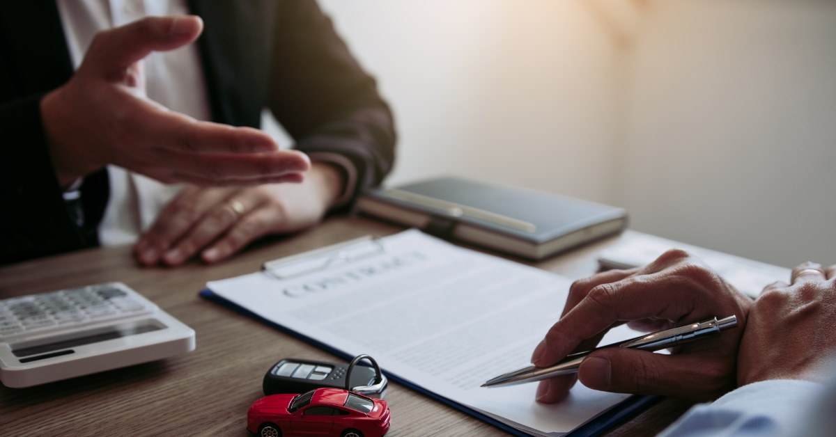 car salesman explaining contract to male client on table with car toys