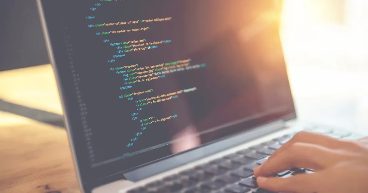 woman writing html code on laptop
