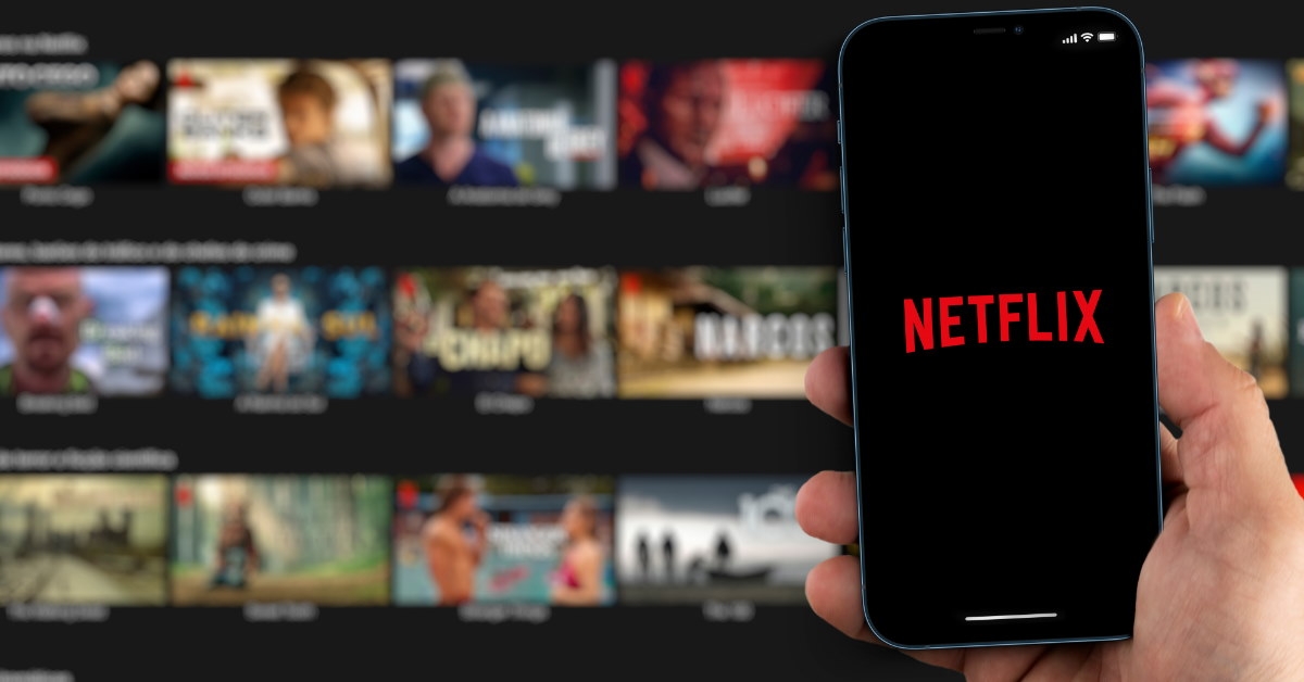 netflix logo on smartphone in man hand with movies in background