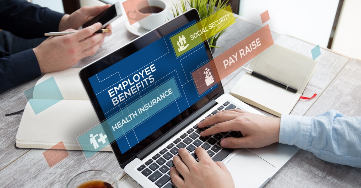 man sitting at table using laptop listing employee benefits