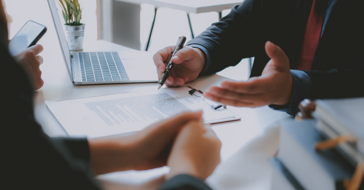 male broker sitting at table explaining documents to client in front of him