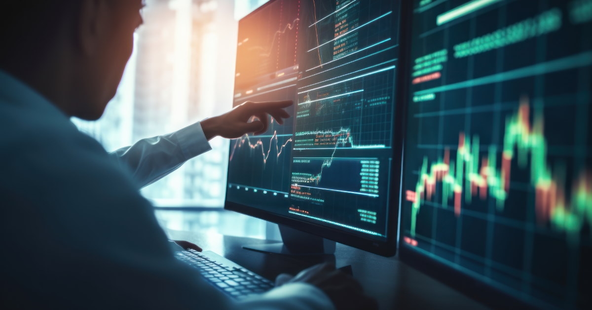male broker sitting at table using computer to check stocks 