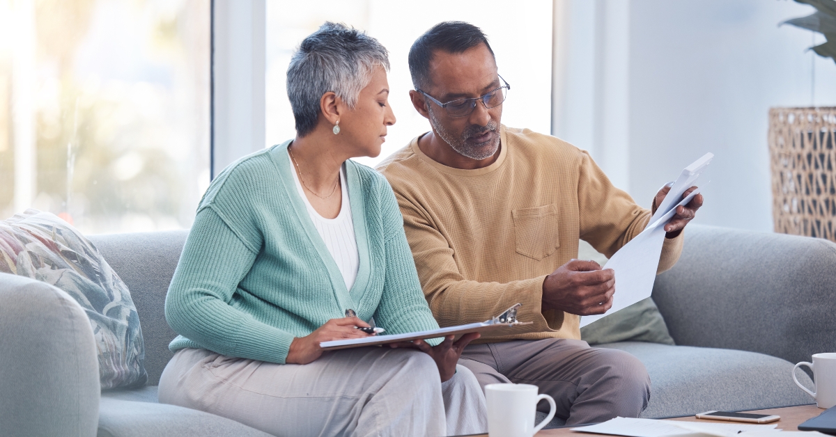 senior couple on sofa with bills paperwork