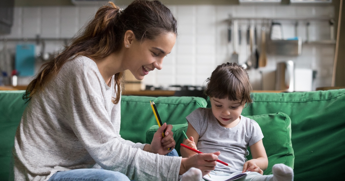 smiling baby sitter and preschool kid girl drawing