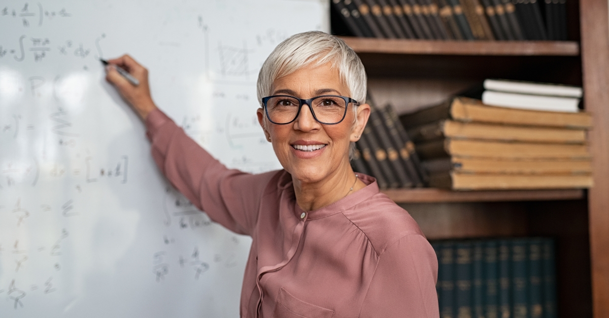 mature teacher writing on whiteboard