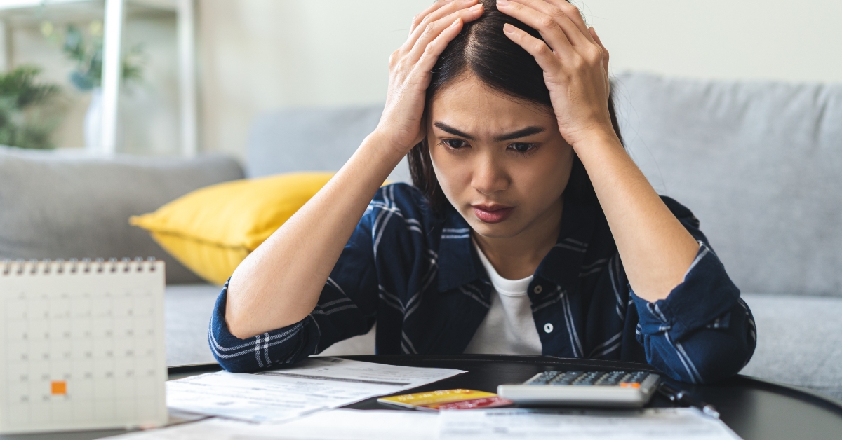 young woman stressed by calculating expenses on table