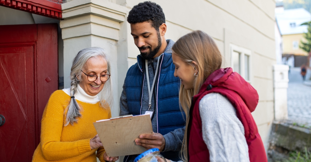 happy young couple standing with senior woman asking for door to door funds